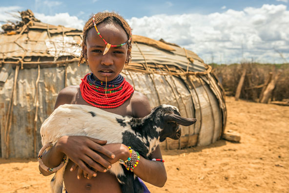 ילדה משבט הדסנץ מחזיקה גדי. בני השבט הם בעיקר רועי צאן ובקר | צילום: Nick Fox / Shutterstock